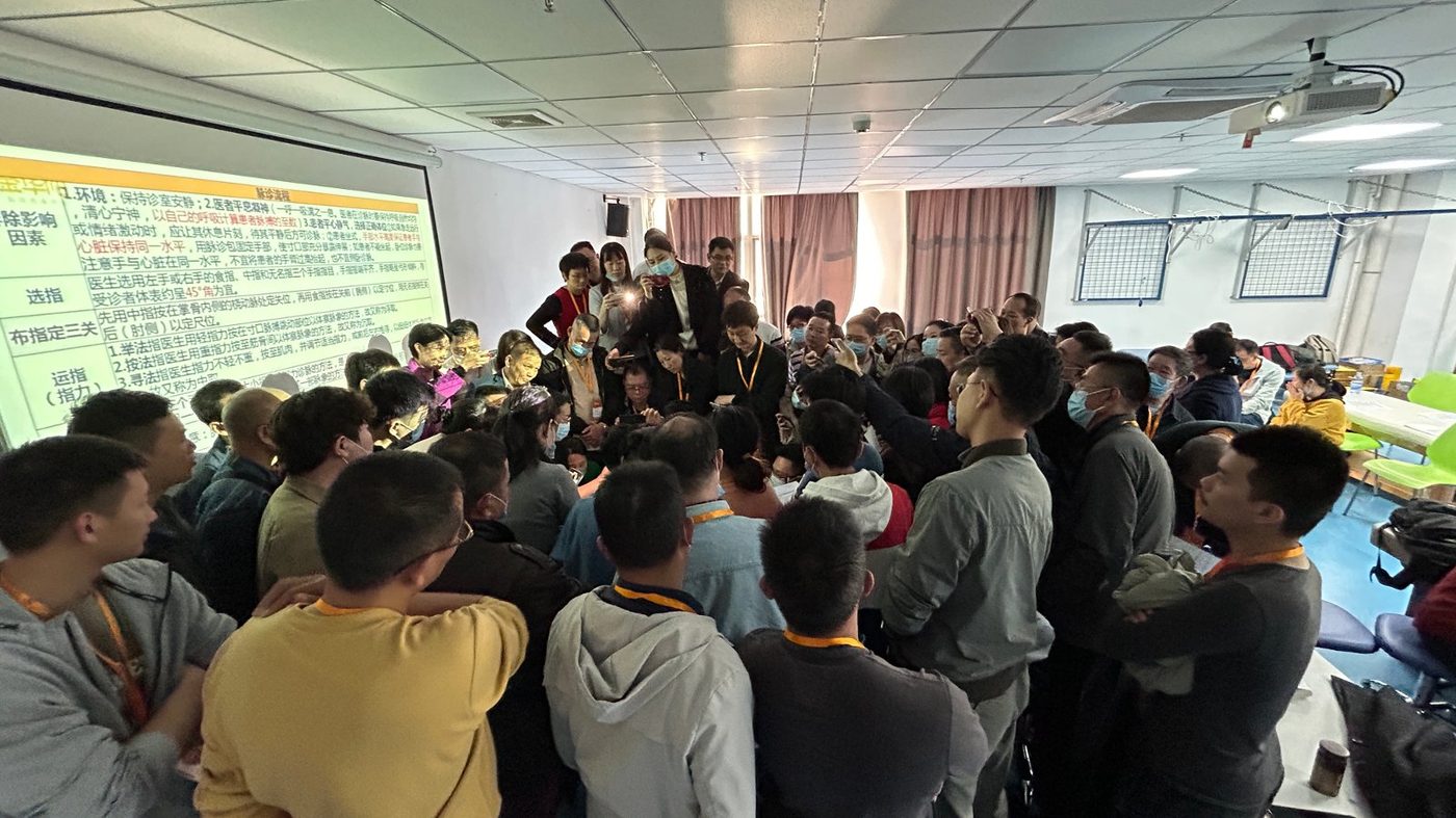 金华佗中医师承线下课程现场,阶梯教室座无虚席,学员在前排认真记录