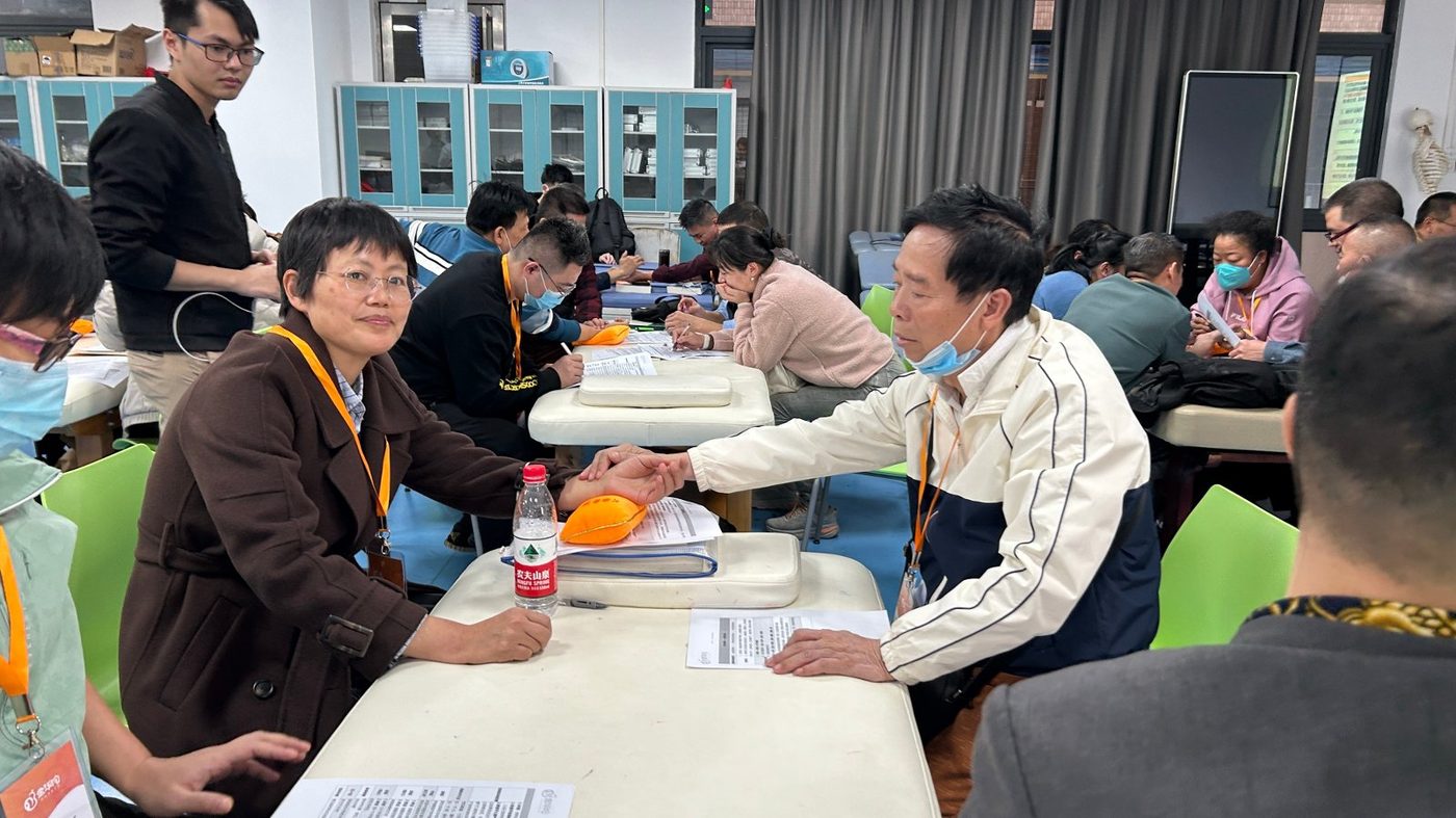 金华佗中医师承线下课程中,讲师在学员座位间逐组答疑指导