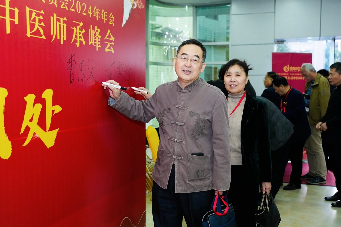 广东省第五届中医师承峰会现场,嘉宾在第五届中医师承峰会签到墙前留影